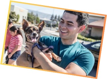 Man smiling while holding his dog outside Napa Humane's Spay/Neuter Clinic.